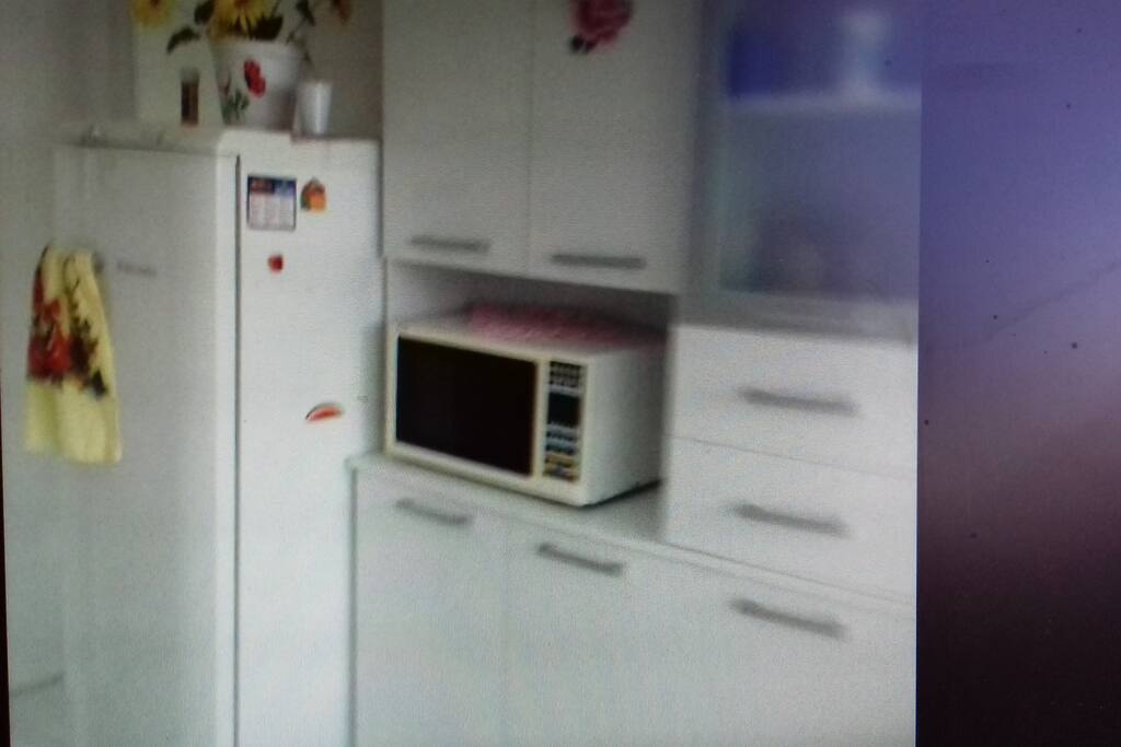 Cozinha equipada com micro ondas,fogão, armário, geladeira e um mesa com cadeiras.
