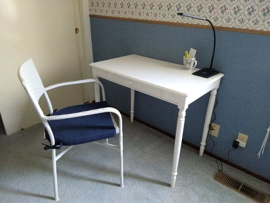 A desk with a pull-out surface for laptops provides workspace for working professionals. An adjustable light adds several levels of light.
