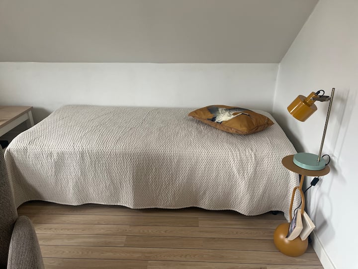 Bed corner in living room. A soft single bed 90 x 200 cm (thus best suited for children/youth or other person of lighter weight). Bedside table and reading lamp.