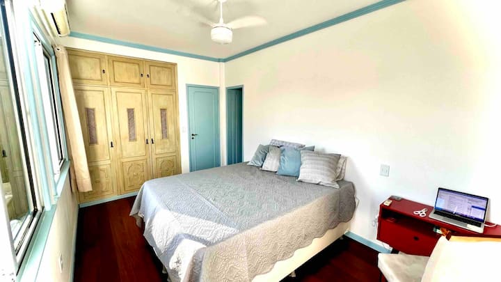 Main en-suite room with double bed, large wardrobe, airconditioner, and working desk with chair. 