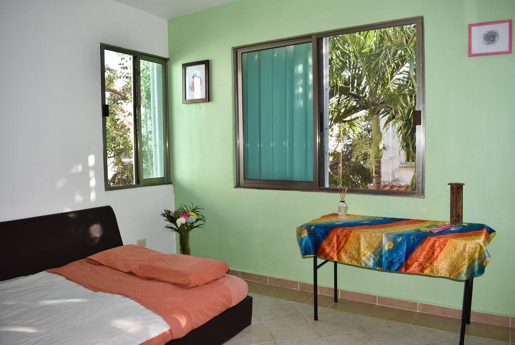 Cómoda habitación para dos personas con cama matrimonial, clóset y mesa para utilizar como tocador.