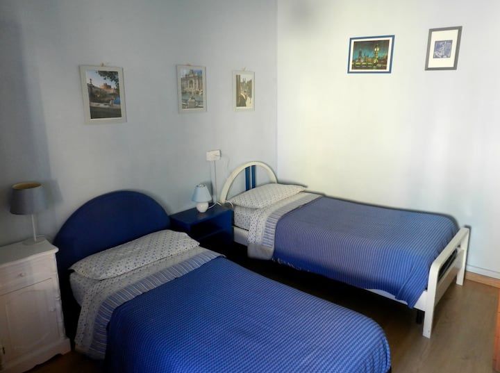 Plava soba s dva kreveta za jednu osobu i dva noćna ormarića s abat-jourom