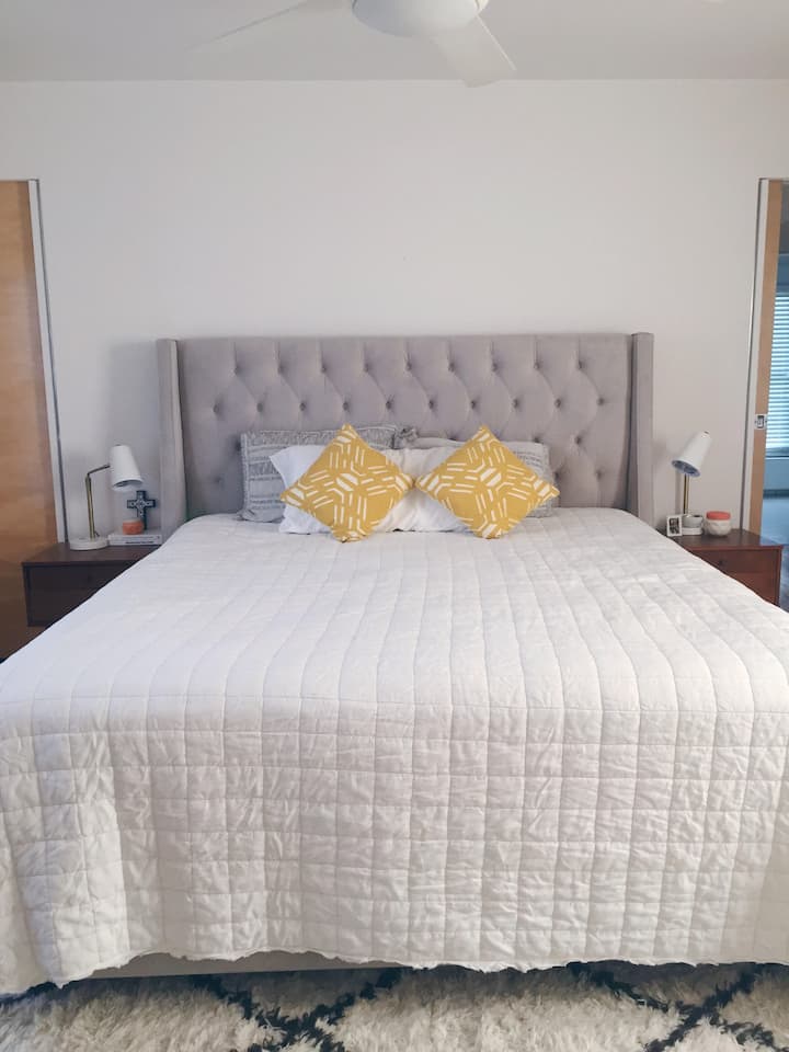 חדר השינה הראשי כולל מיטת קליפורניה קינג סייז, מזרן לטקס אורגני ומצעים בסגנון בוקיצה מערבית.