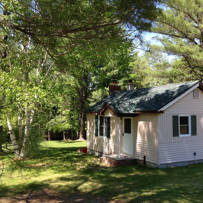 The cabin property extends across lush lawns, into the forest, and down to the Ausable River.