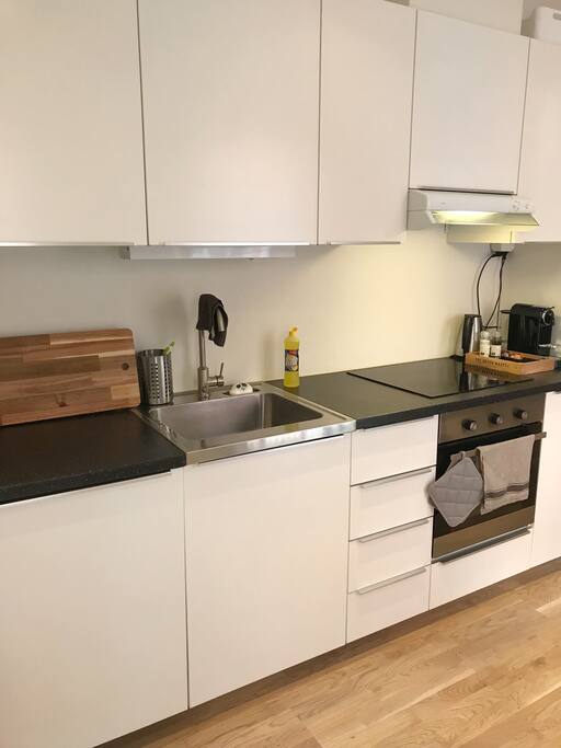 Kjøkken med ovn, oppvaskmaskin, vannkoker, kaffemaskin og kjøleskap.