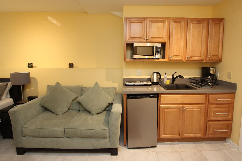 Love seat. Mini-kitchen with microwave, mini-fridge, electric plate stove, coffee maker, and full kitchen-ware.