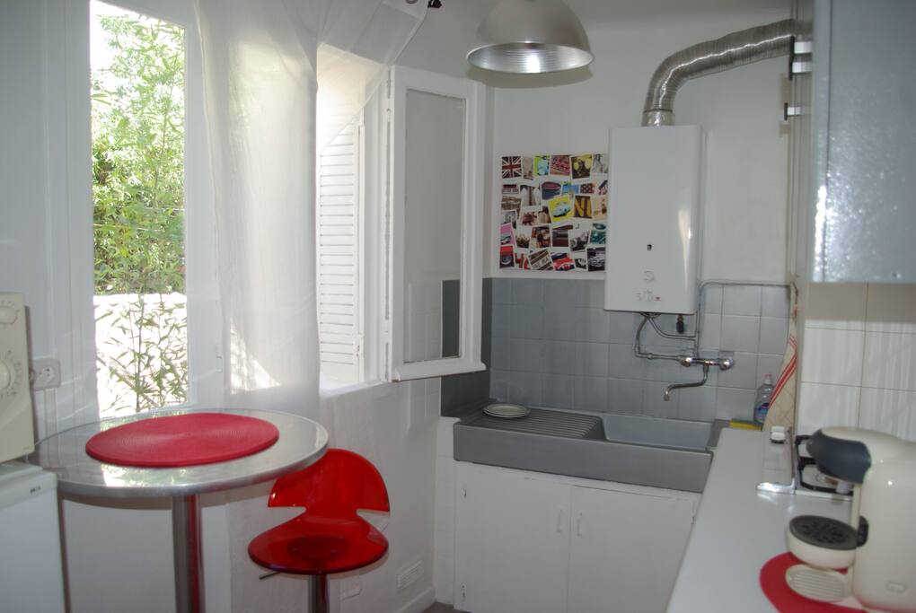 Cuisine lumineuse avec table bar, deux plaques de cuisson, cafetière à dosettes, frigo, congélateur et tout le nécessaire en vaisselle et produits ménagers