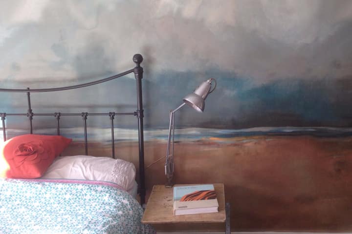 Stylish bedroom area with incredible wall paper scene of Holkham beach