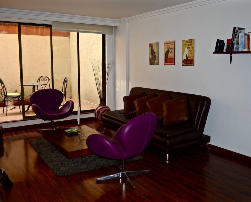 Sala principal con salida a la terraza. El sofá café oscuro es el sofá cama donde puede dormir otro huésped.