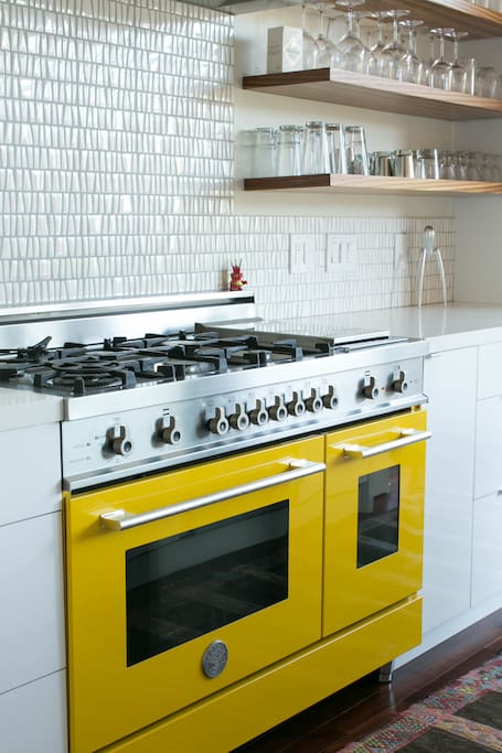 Foodies will love cooking on the yellow Bertazzoni range with 6 burners, griddle, and two ovens.