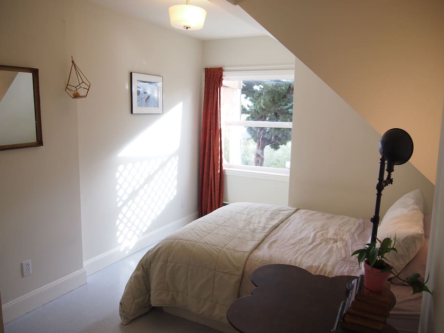 The full/queen bed looks out onto the backyard through a wide window