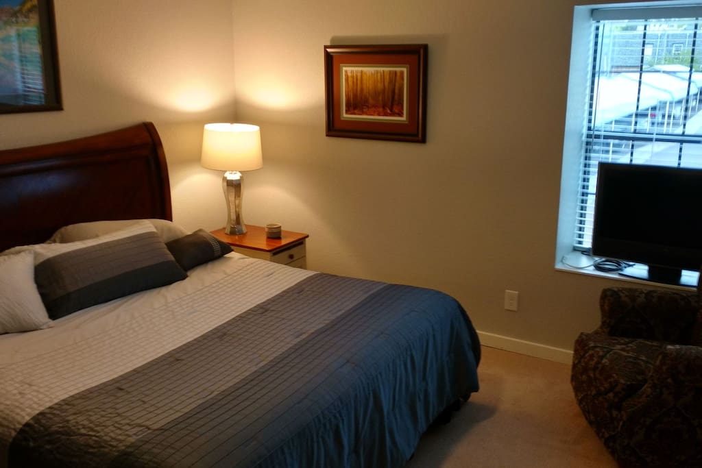 Comfortable bedroom with TV and chair.