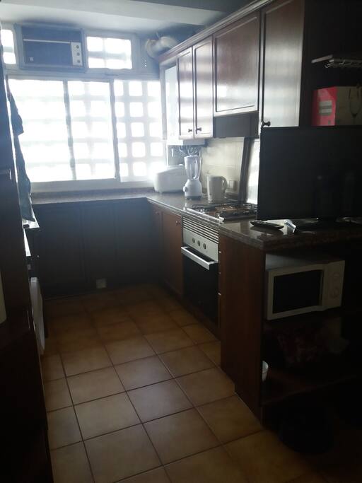 Cocina equipada con nevera, horno, microondas, televisión, mesita con sillas, calentador de agua para infusiones y batidora para batidos. También hay espacio en los muebles y la nevera para guardar comida.