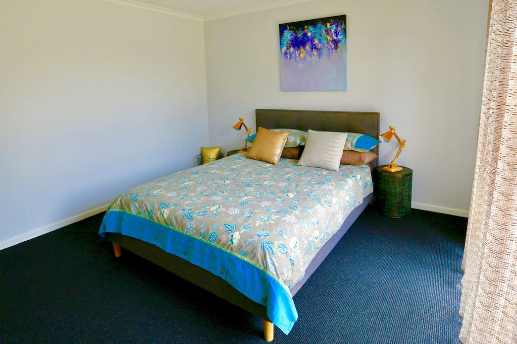 Queen Bed. Large bedroom with BIR. Lamps either side of bed and PowerPoints for charging devices.