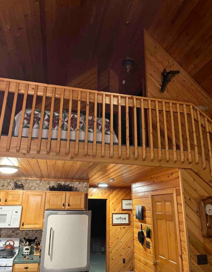 View of queen bed on loft from main level. Bunk room with twin and 3 bunk beds in closed room behind it