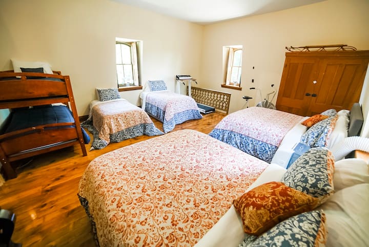 The Great Room has two queen beds, two single beds and a bunk bed.  The original railing is for the back stairs which lead down to the 2nd floor bathrooms.  The three windows open to the north, east, and south.