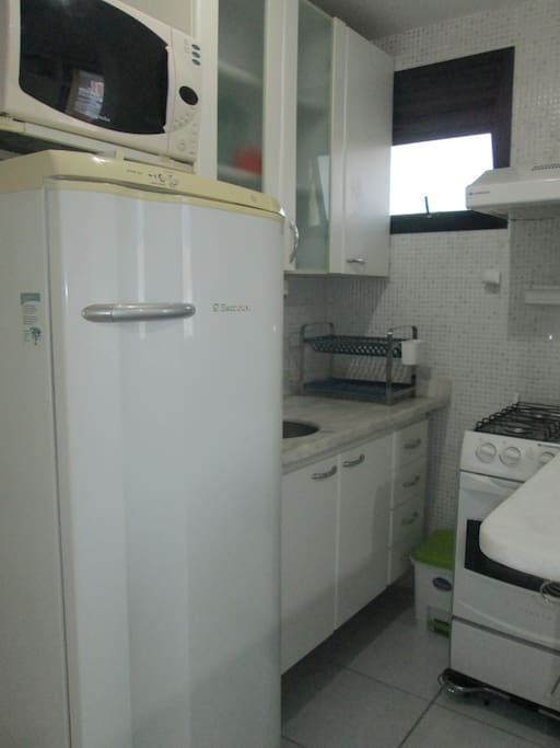 Cozinha equipada com fogão, geladeira, micro-ondas e utensílios.