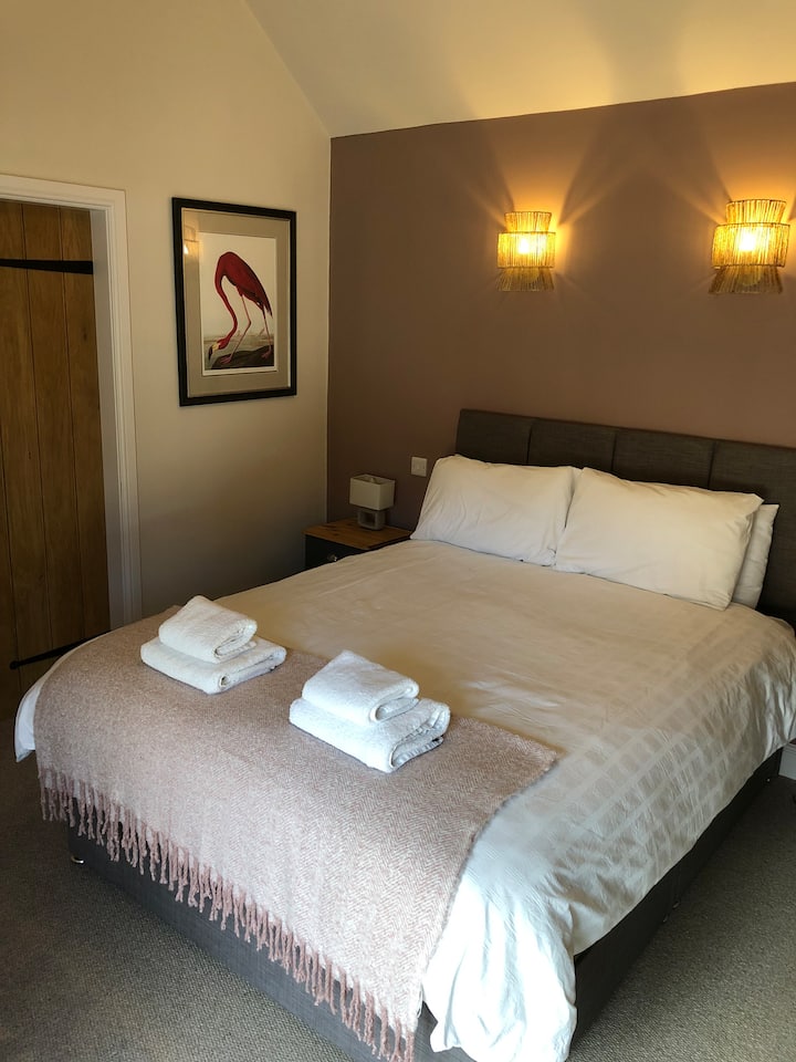 Საძინებელი ერთი დიდი ზომის საწოლით, ფლიგელით, სმარტ-ტელევიზორით, ჩაშენებული კარადებით და იატაკის ქვეშ გათბობით 