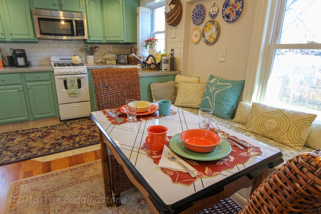 Eat-in kitchen w/ bench seat, dishwasher, dinnerware and all cooking essentials.