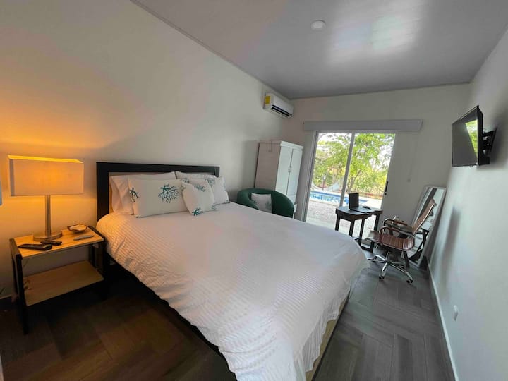 Chambre avec vue sur la piscine et espaces verts avec lit queen, lit superposé avec lampe, closeth, bureau de travail en bois avec chaise, miroir et table basse, télévision écran plat avec Netflix