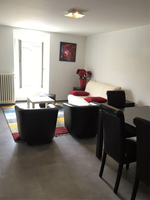 Dans la grande pièce à vivre le coin salon avec canapé convertible, meuble salon avec télé écran plat et 2 petits fauteuils
