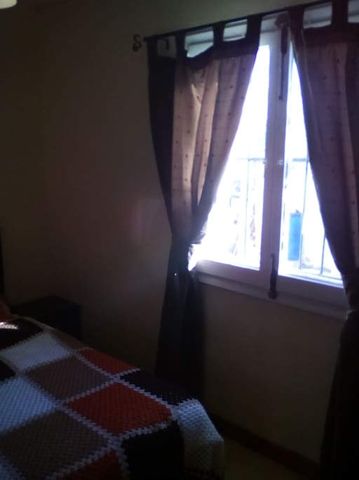 Old fashioned wooden windows with tab top curtains and tie backs.