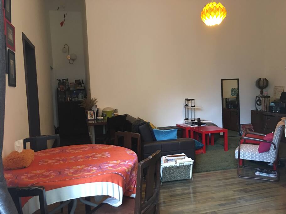Dining area - table folds into half. White adjustable work desk on red coffee table can be used as standing desk. Sofa can be converted into a daybed.