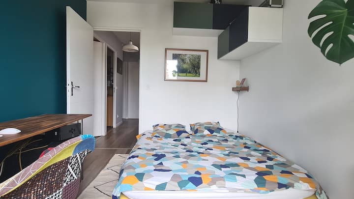 Spavaća soba s pogledom na radni stol, računalo i park.  