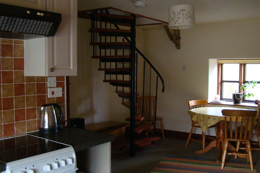 living space with spiral stairs leading to bedroom
