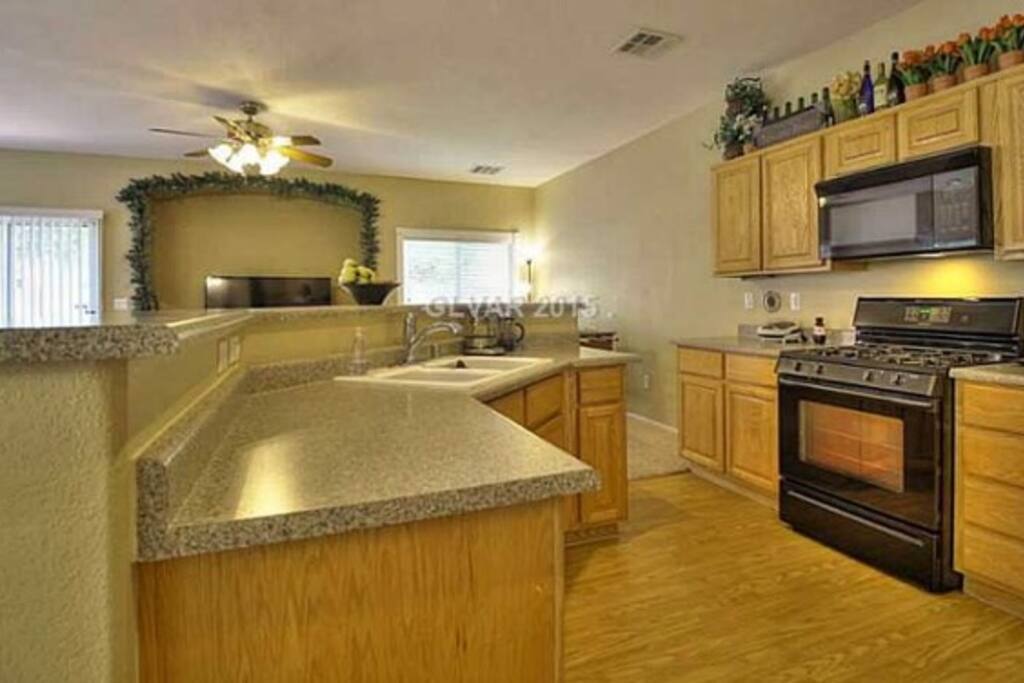 Full kitchen view with stove, refrigerator, bar island and food panty for (food) storage.