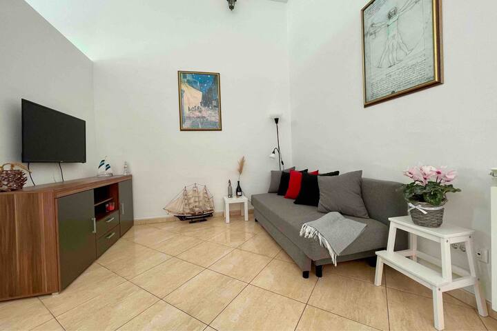 Sala de estar con sofá cama y TV plana.