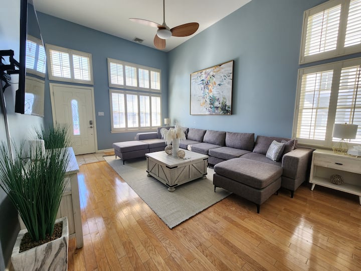 Spacious, bright and comfortable living room with section couch, ceiling fan and TV. 