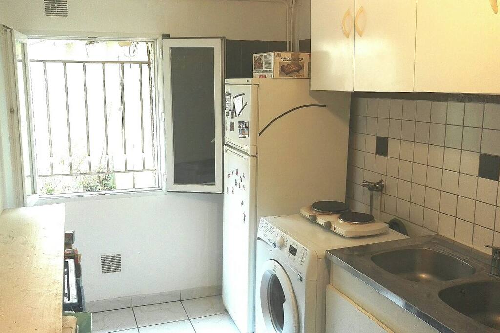 Cuisine avec frigidaire, congélateur, plaques de cuisson, lave linge et four