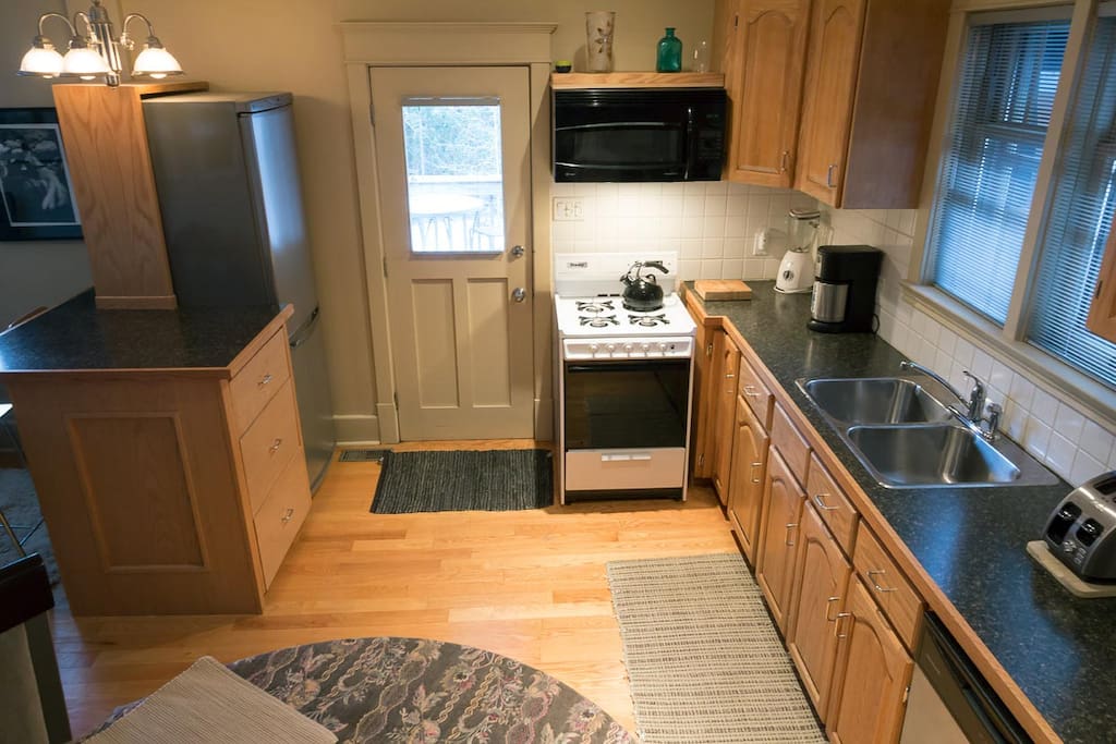 Kitchen with fridge/freezer, gas stove, double sink, dishwasher, convection/microwave/fan above stove. Gas barbecue just outside the door on deck.