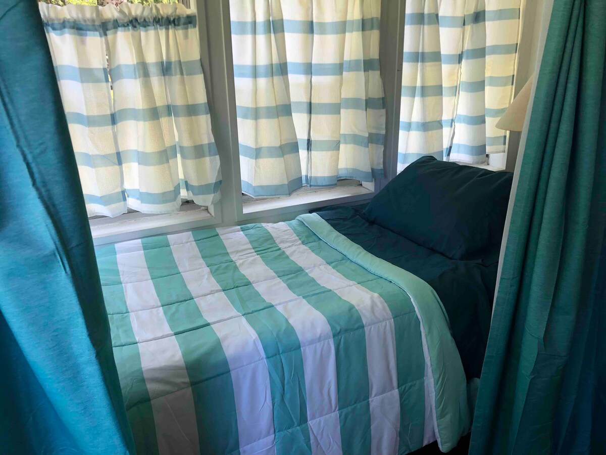 Porche con cuna doble.  Con vistas al lago con algunas vistas al lago y algunas vistas a través de los árboles en verano. Puedes escuchar a los lobos y el lago.  Cortina de privacidad, colchón de aire doble y ventilador para mayor comodidad. (El colchón de la cuna es fino, bueno para niños.