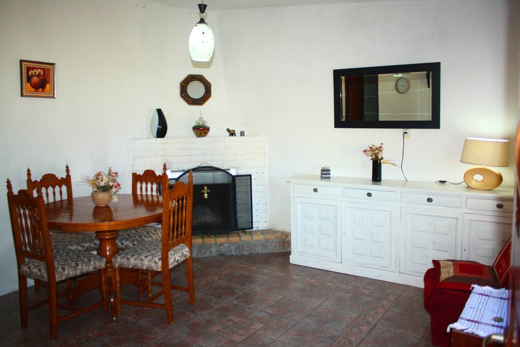 Living/comedor con mesa para cuatro personas, con estufa a leña y televisión led con Direct tv