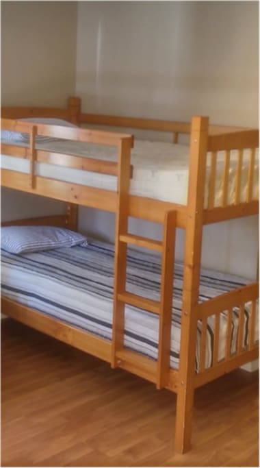 Small Room with bunk beds. 3 Twin Beds. Desk and Chair under 1 bunk.