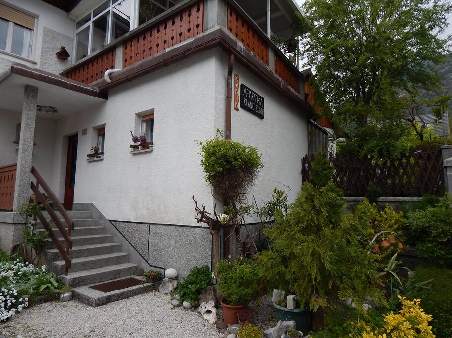 Entrance to Apartment Raft with a glimpse of the outdoor dinning and BBQ area in a traditional Slovenian garden.