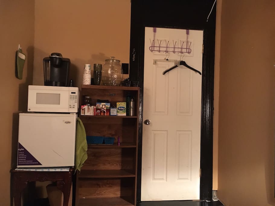 Taken from sitting on the bed. Mini kitchen area with mini fridge, microwave, coffee maker, 2 gallons of water, silverware, plates, bowls, cups, coffee, creamer, tea, can opener, bottle opener, etc. Hooks on the back of door for towel, jackets, etc.