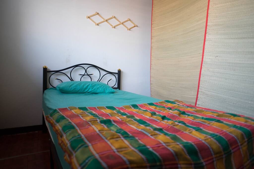 Single bed at dorm room with the bamboo curtain.