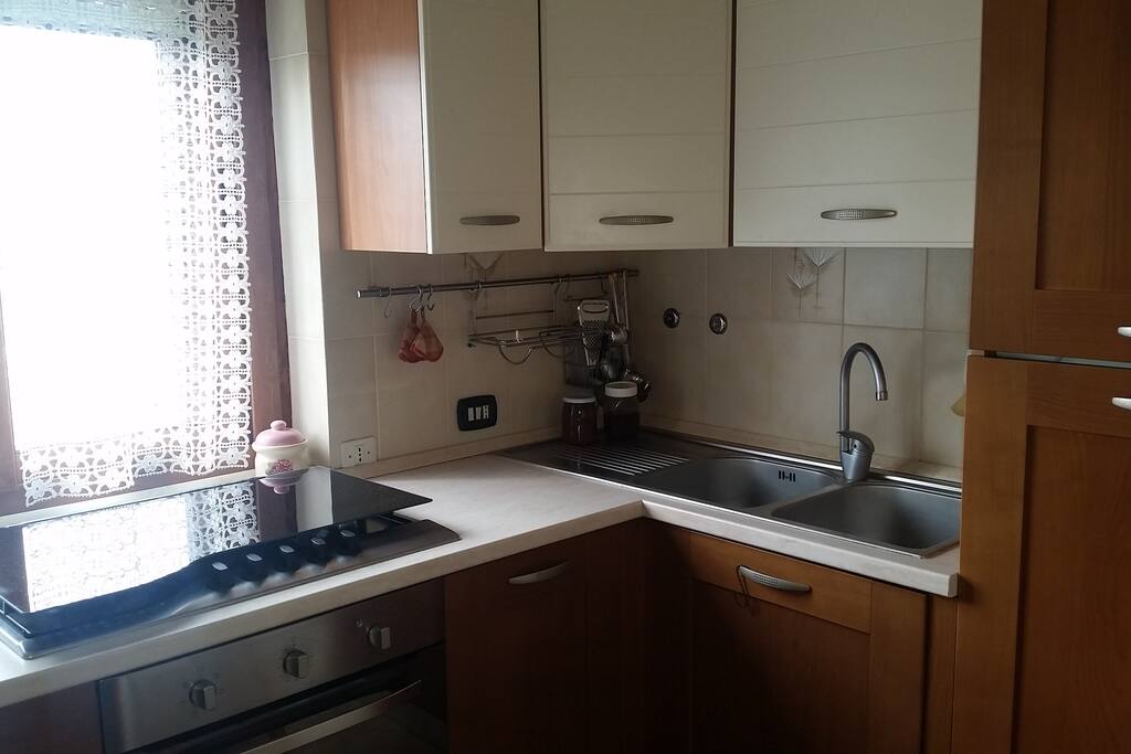 Cucina con lavastoviglie, frigo e utensili vari