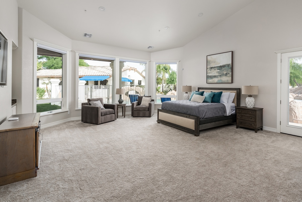 [Dormitor principal] Pat matrimonial cu baie proprie, zonă de birou și zonă de relaxare cu vedere la curtea din spate.