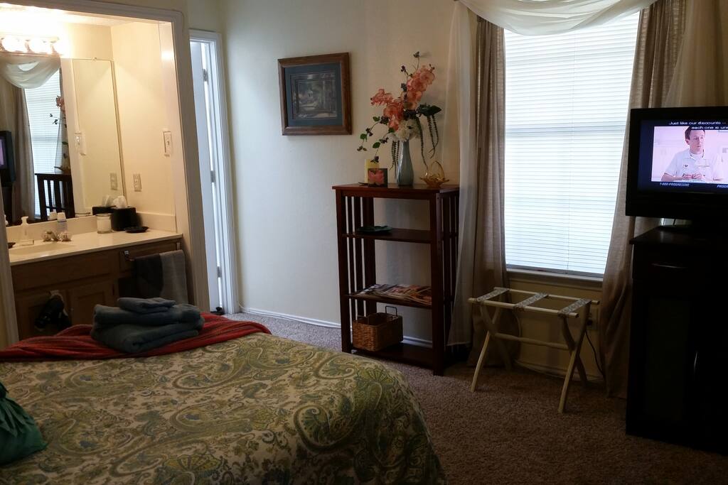 Across the bed to the window, tv, bathroom door and vanity area