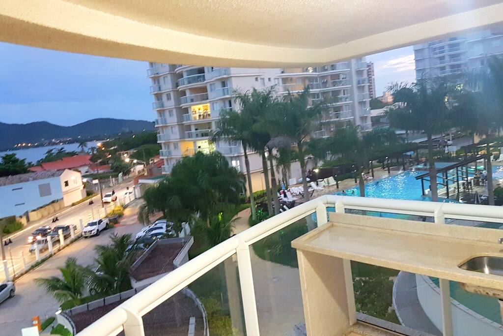 Vista da sacada: mar e piscina.