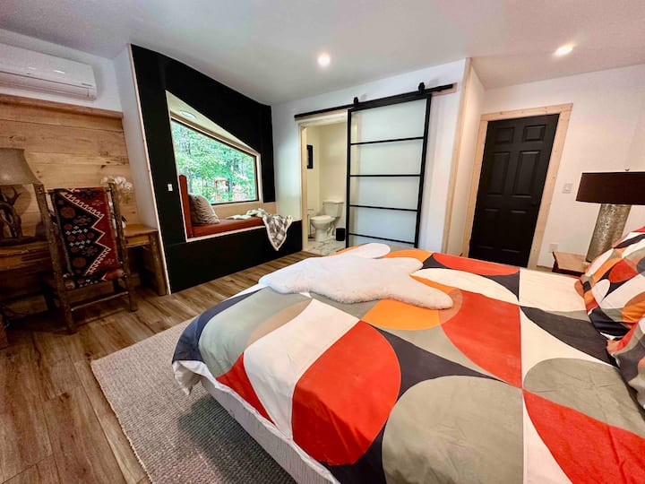 Голяма родителска спалня с двойно легло и собствена модерна баня, бюро на работна станция и кът за четене на прозорци. 