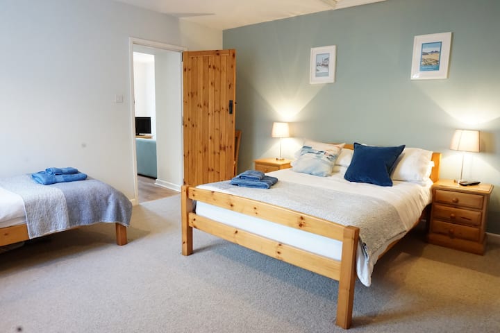 חדר שינה גדול עם מיטת יחיד זוגית, ארון בגדים זוגי, שידת מגירות וטלוויזיה. 