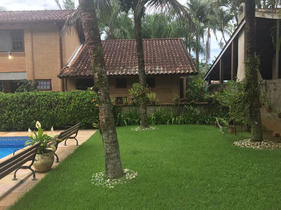 Vista da area dos quartos, com gramado, coqueiros e piscina