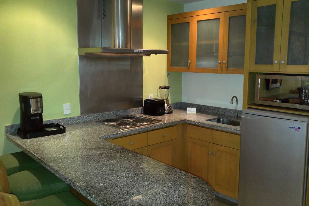 A well-equipped kitchen features granite counters, cooktop, microwave, pots and pans, and full complement of dishes, cutlery and glassware