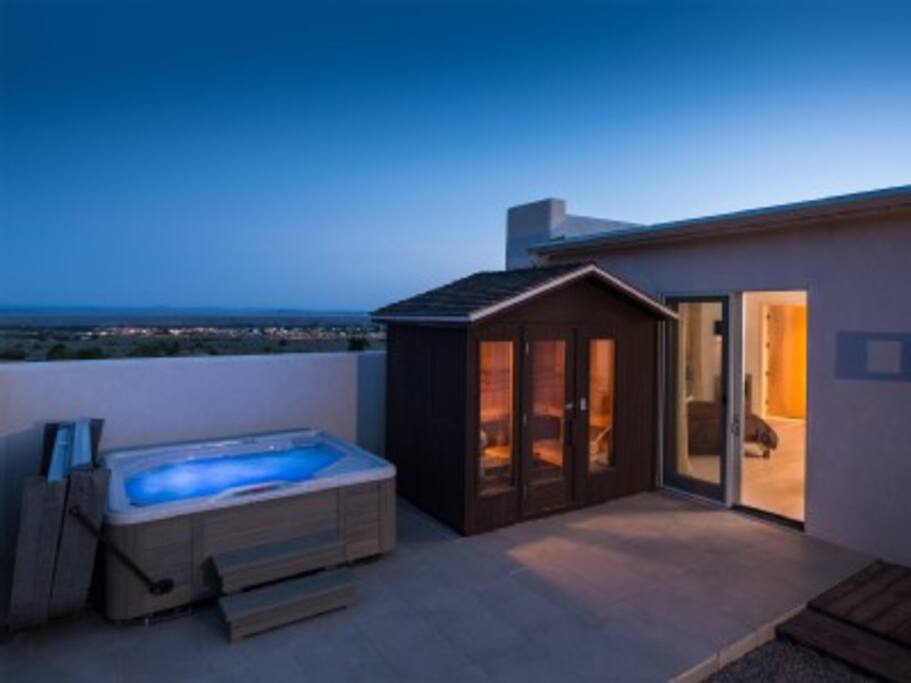 Outdoor hot tub and sauna with glass wall.