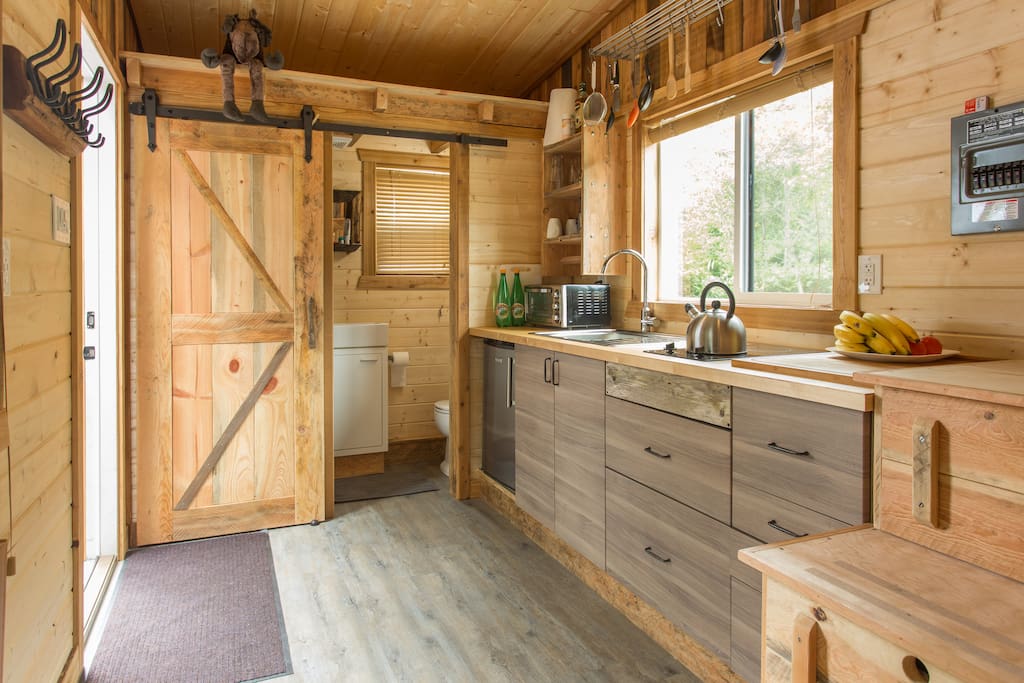 Great feeling with all the wood inside the Tiny House. Fridge, two burners and a toaster oven. Bathroom with shower, sink and toilet behind a sliding door.